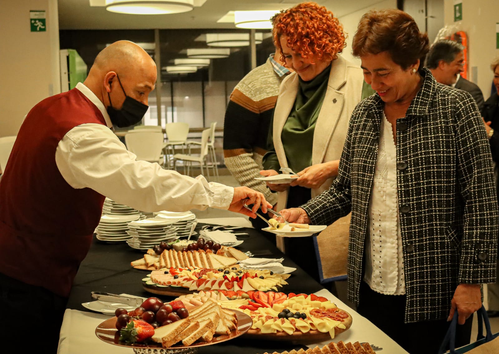 Mesero profesional de VIP Catering sirviendo una tabla de quesos gourmet en un evento social