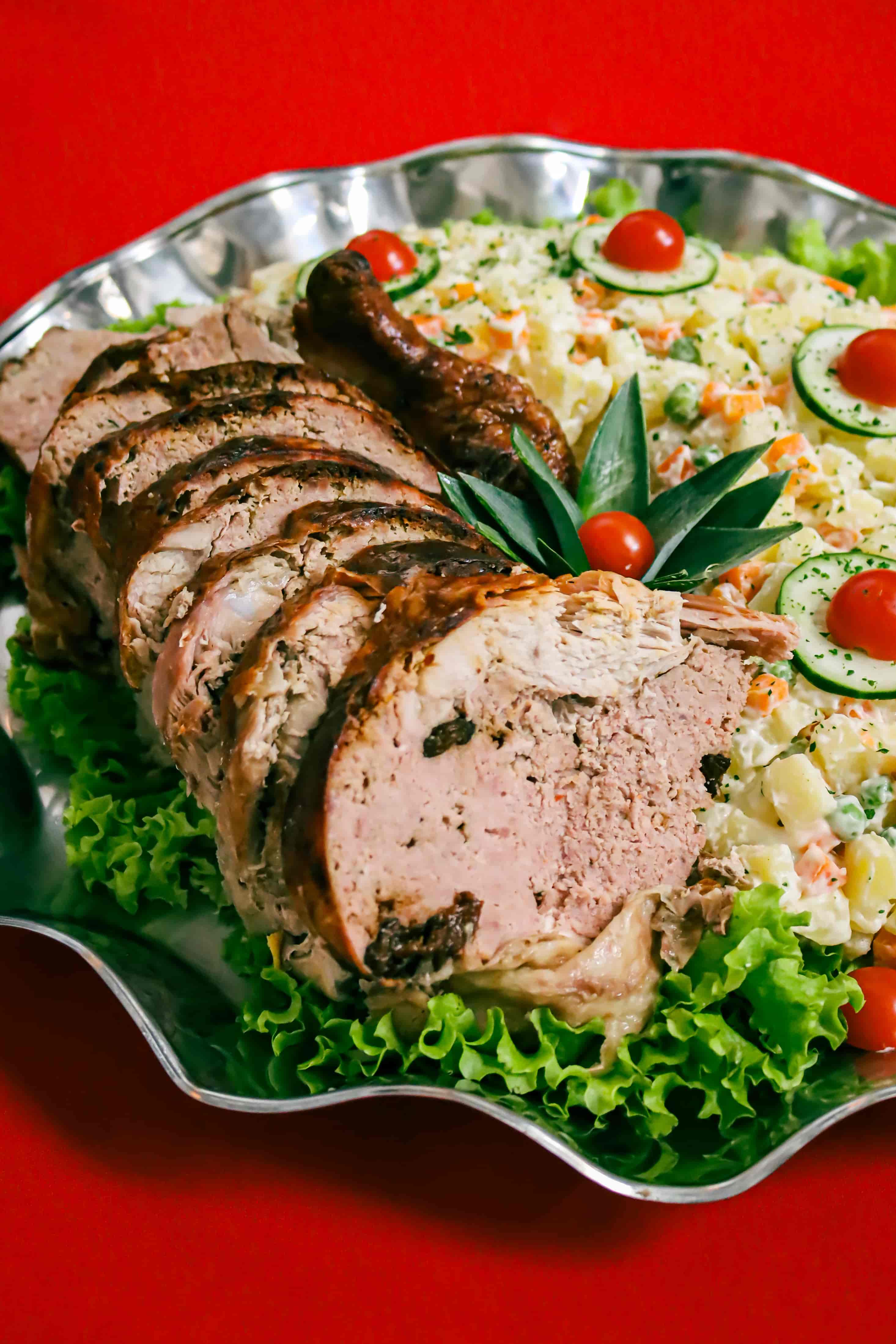Pavo relleno acompañado de ensalada rusa presentado en bandeja para catering de eventos corporativos.